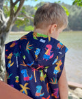 Dinosaur print swim parka. Boy is standing at beach wearing a swim parka. Schmik swim parka has removable sleeves and dinosaur print. 