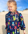 Toddler wearing dinosaur swim parka in navy print. Schmik swim parka can be worn after swimming lessons and nippers instead of a towel. Schmik swim parkas can be bought on Amazon.com