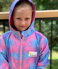 Child wearing mermaid print swim parka with hood on. Schmik logo is visible on jacket. 