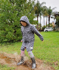 Girl jumping in muddy puddles wearing a schmik swim parka with skull print. Schmik swim parka has a showerproof outer, ideal for walking in the rain. 