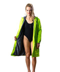 Adult lady wearing swimmers and a schmik swim parka in fluro green. Flluro green swim parka is unzipped. 