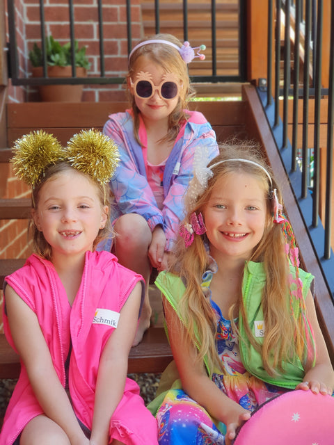 3 happy children wearing bight and funky schmik swim parkas. Mermaid print, fluro green and fluro pink swim parkas. 